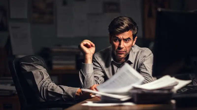 Persona confundida, escritorio desordenado, ambiente tenso